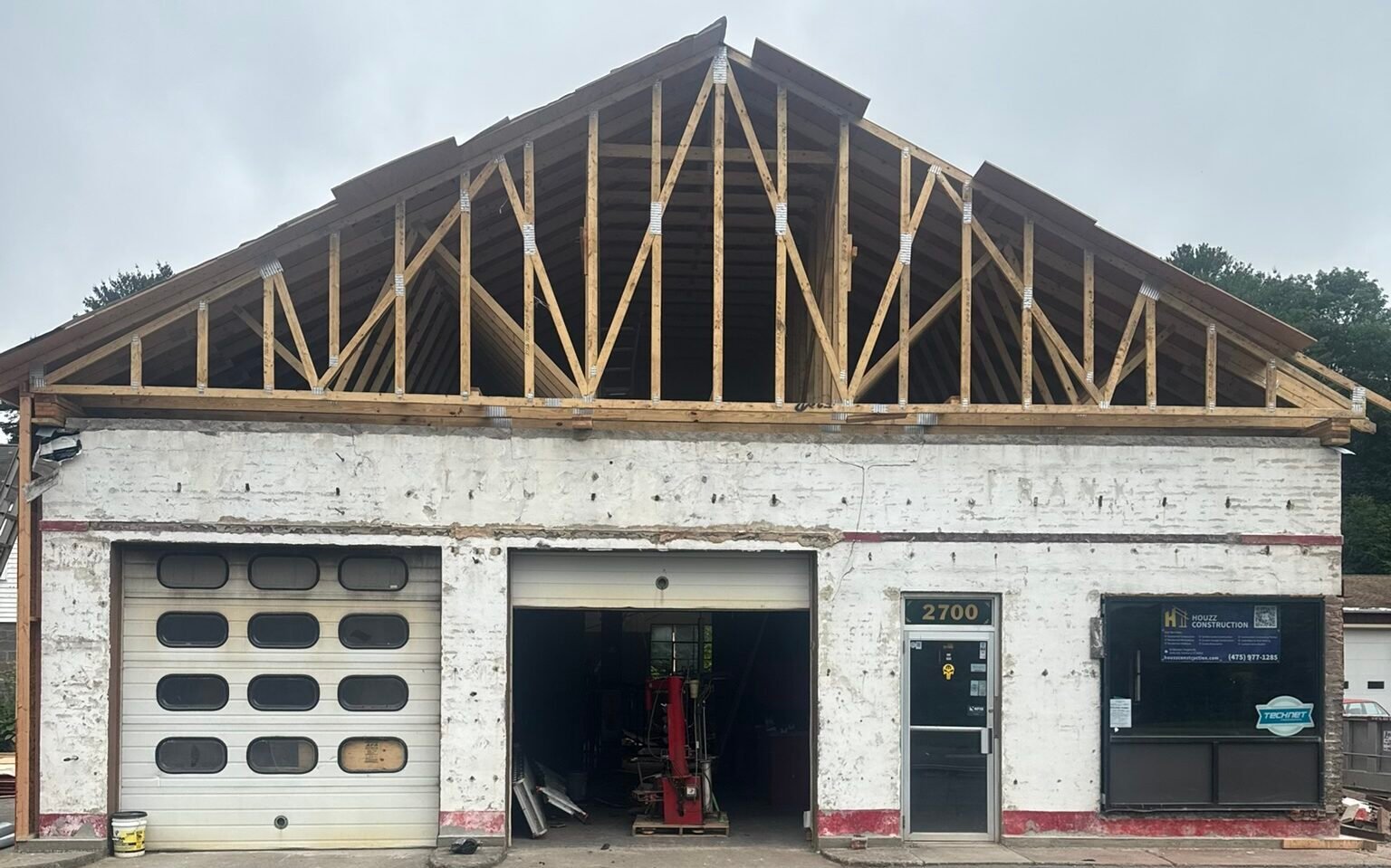 Early renovation work with exposed roof trusses above the original garage facade